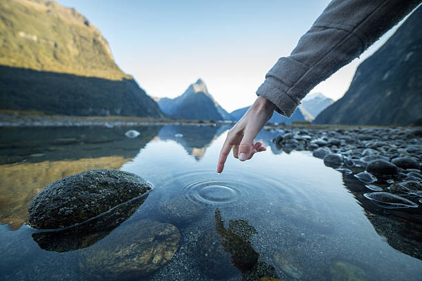istock Finger touches surface of mountain lake 618031808