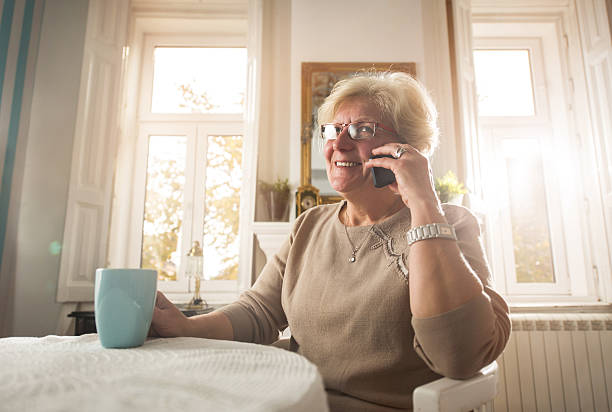 femme âgée heureuse parlant sur le téléphone portable à la maison. - women telephone senior adult on the phone photos et images de collection