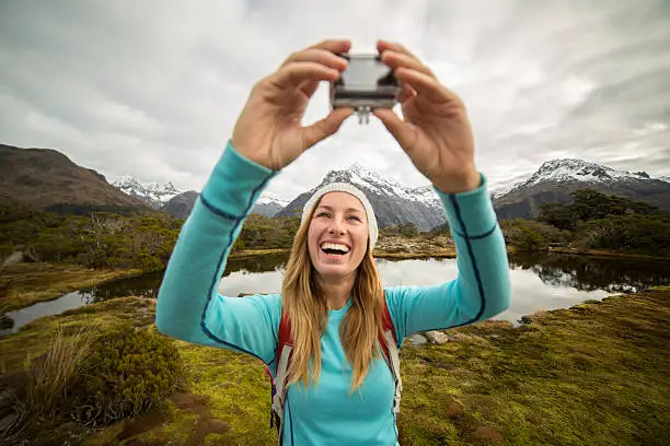 Young female hiking in Autumn takes a selfie portrait using a wearable camera.