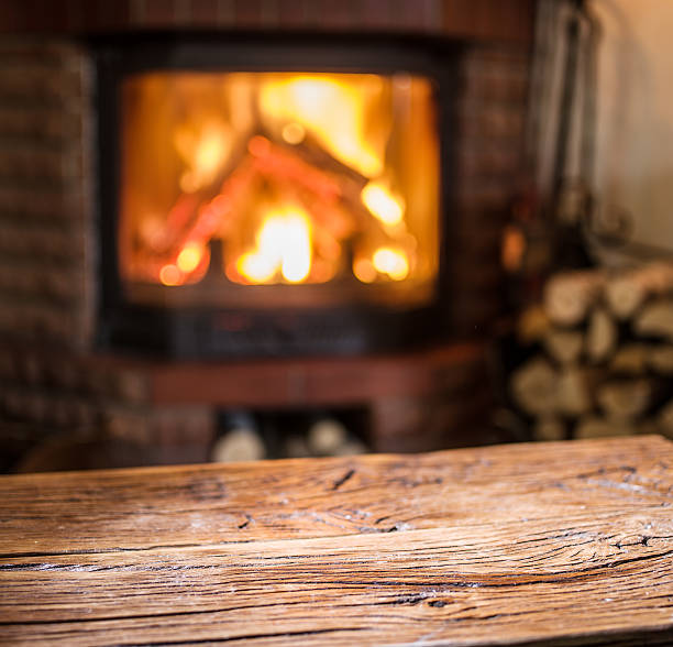 istock Old wooden table and fireplace with warm fire. 618041764
