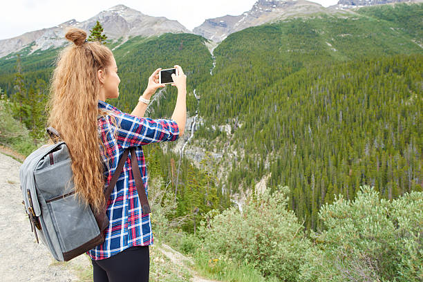 istock Young beautiful female backpacker doing pictures on her phone 618041796