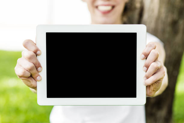 young woman showing digital tablet with blank screen at park.close up.