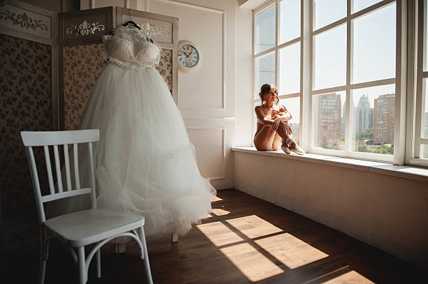 Beautiful young ballerina in pointe pretty young ballerina in pointe puts on a dress in a big white room with large windows wedding hall stock pictures, royalty-free photos & images