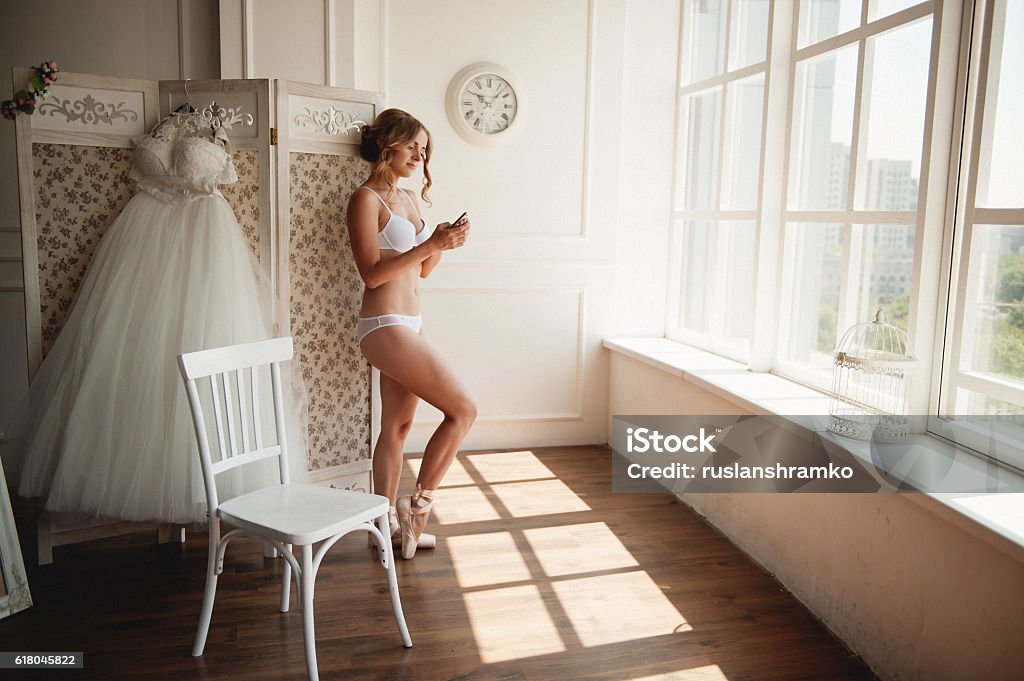 Beautiful young ballerina in pointe pretty young ballerina in pointe calling on the phone in a big white room with large windows Bride Stock Photo