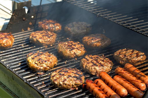 Cheeseburgers, hamburgers and hotdogs being grilled