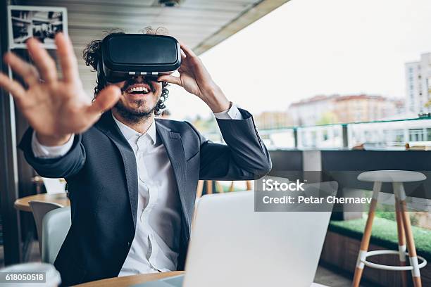 Photo libre de droit de Jeune Homme Regardant À Travers Une Réalité Virtuelle Et Gesticulant banque d'images et plus d'images libres de droit de Réalité virtuelle