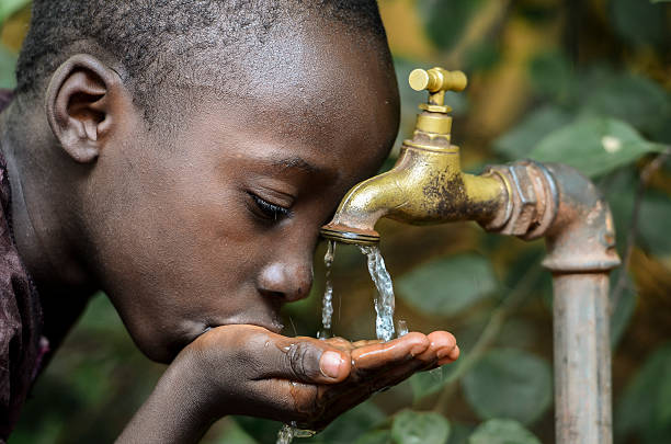 Little African Boy Drinking Healthy Clean Water from Tap stock photo