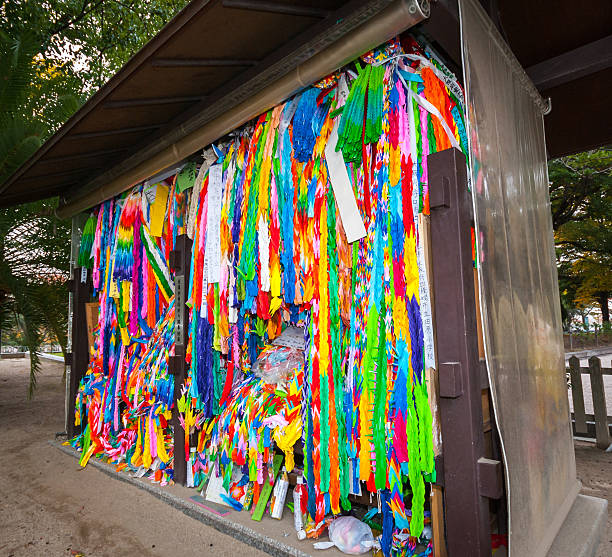 Hiroshima, Japan - November 13, 2010: Multicoloured paper cranes folded by school children from across the world on display at the Children's Peace Monument in the Hiroshima Peace Memorial Park.  Signs are messages of peace.