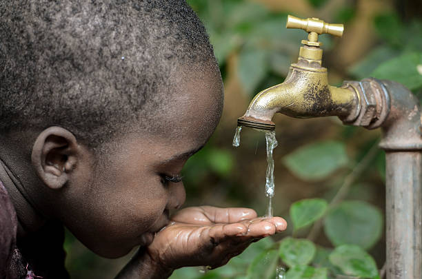 istock Baby Boy Drinks Water from Tap in a Garden 618053610