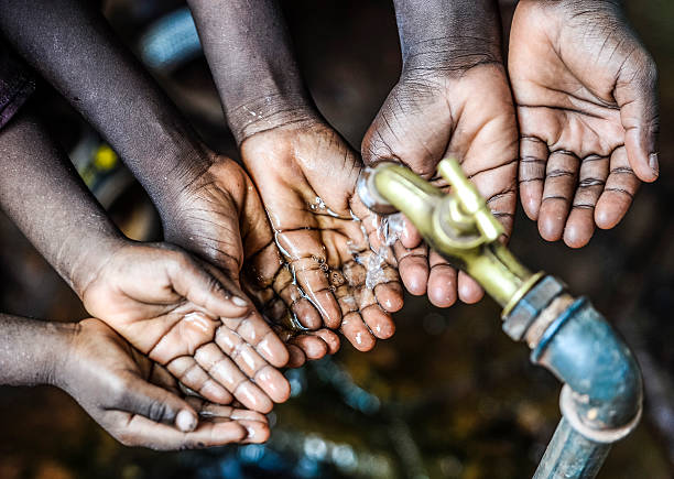 Fresh Water for Africa Symbol by Black Children Three African children holding their hands under a tap. Symbol for the importance of water in African countries. water crisis stock pictures, royalty-free photos & images