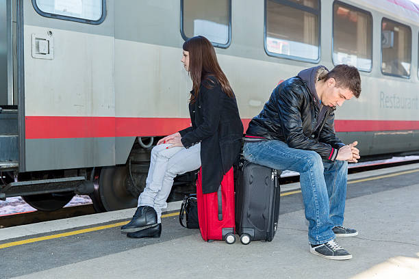 istock Young couple with suitcases waiting for a train...railway station 618057624