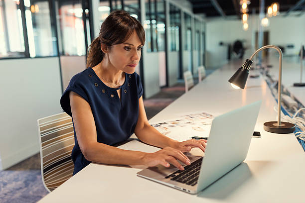 istock Concentrated middle aged woman focused on her laptop screen 618059026