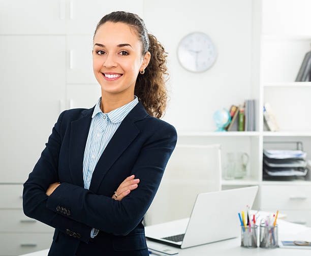 young business lady in office Smiling young business lady with dark hair standing near office desk chief leader photos stock pictures, royalty-free photos & images