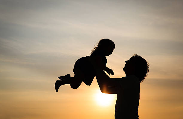 istock Father and little daughter silhouettes at sunset 618064266
