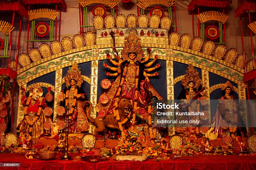 Goddess Durga at yearly festival in Pune Pune, MH, India - October 10, 2016: Taken this picture in Pune during Festival of Durga Puja of bengali community. In the picture tried to capture the hindu idol of goddess durga; in foreground are the offering devotees offered which includes flowers,clothes, oils, etc. Goddess durga depicts power of woman destroying evil and lion showcasing the power of the goddess. Allegory Painting Stock Photo