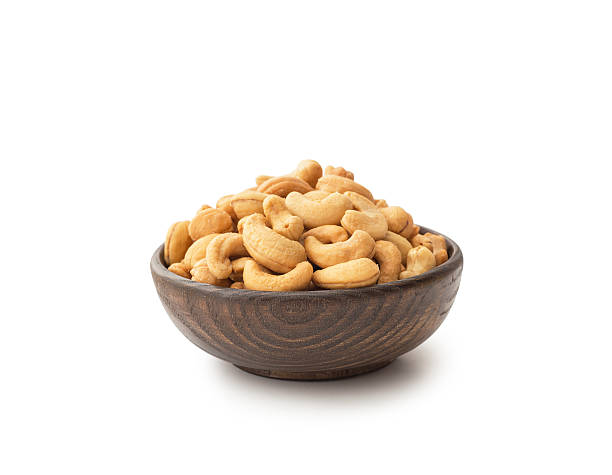 Cashews with wooden bowl Cashews with wooden bowl , isolated on white cashew stock pictures, royalty-free photos & images