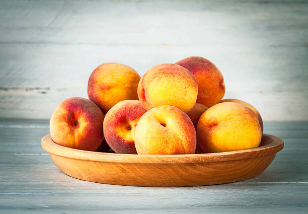 istock Fresh peach on wooden plate and board 618069622