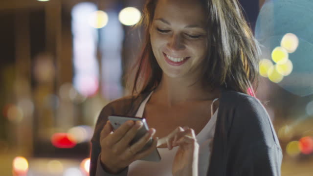 Attractive Woman using Mobile Phone During Walk on Streets of Night Town