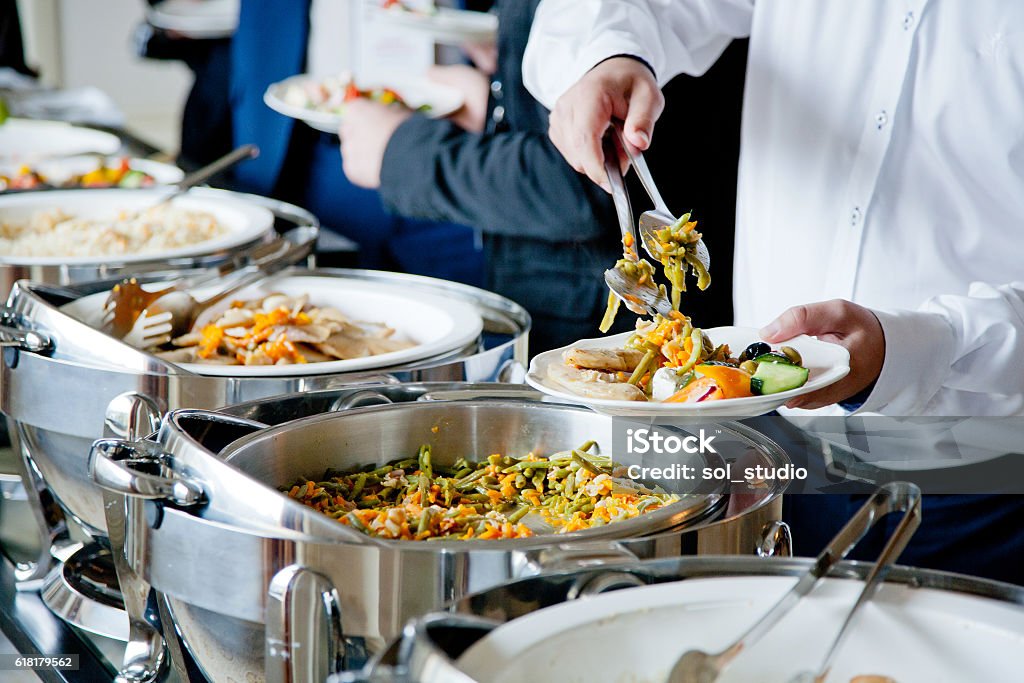 people at a banquet men in blue suits choosing food at a banquet Buffet Stock Photo