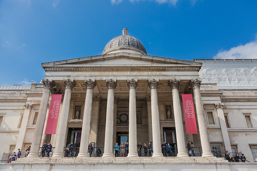 London, UK - May 14, 2016; The National Gallery is the main art museum in London, located on the northern edge of Trafalgar Square in the municipality of Westminster, in the center of Greater London. There are people walking between columns