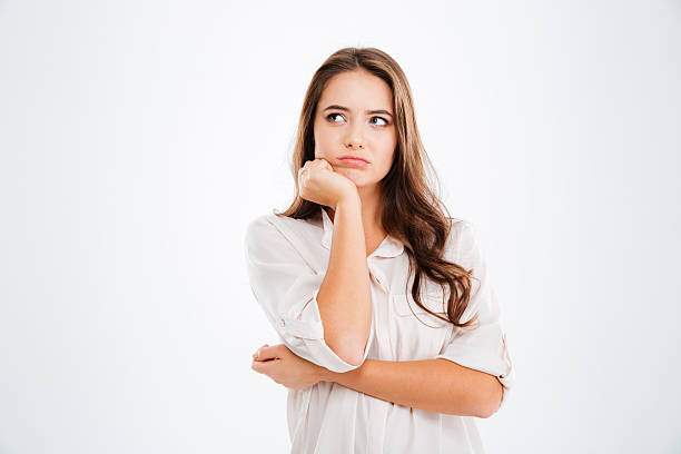 Thoughtful cute young woman standing and thinking Thoughtful cute young woman standing and thinking over white background suspicion photos stock pictures, royalty-free photos & images
