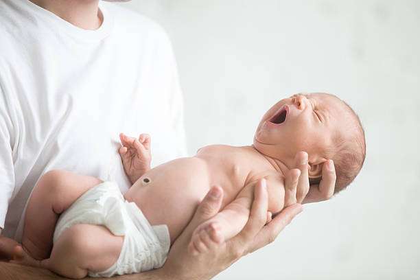 istock Male hands holding a screaming newborn 618185462