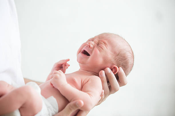 portrait of a screaming newborn hold at hands - new childbirth new life love imagens e fotografias de stock