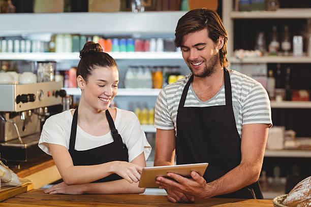 istock Smiling waiter and waitress using digital tablet at counter 618185978