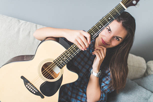 istock Young woman on sofa holding guitar 618188658
