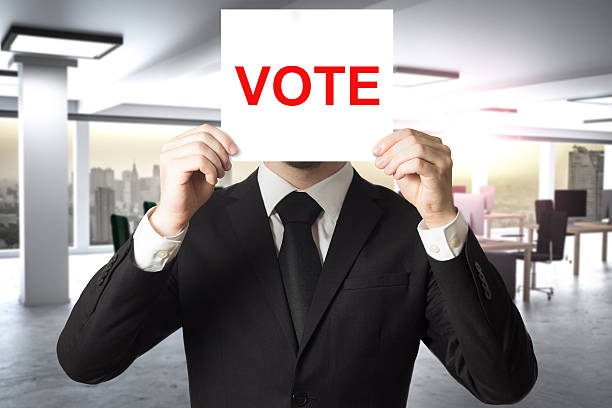 istock businessman hiding face behind sign vote 618192618