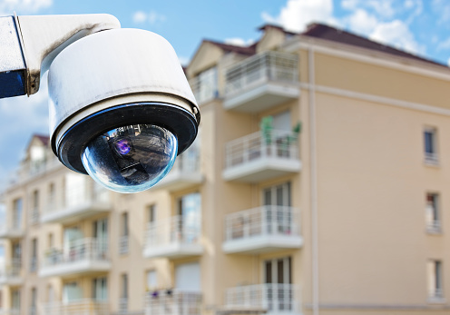 security CCTV camera or surveillance system with modern luxury residence on blurry background