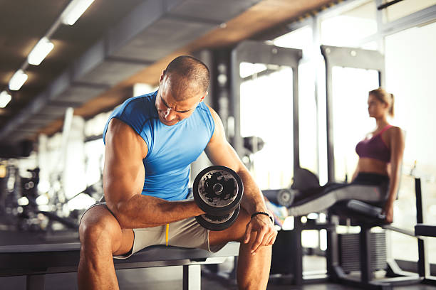 jovem homem musculoso levantamento de halteres em o ginásio. - flexing muscles bicep men human arm - fotografias e filmes do acervo