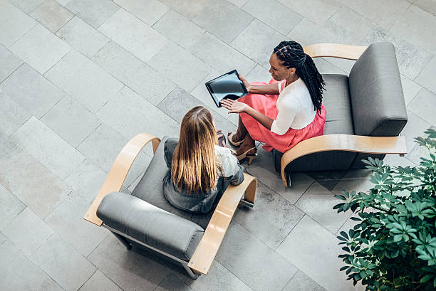 Overhead view of women working together Overhead view of two business women having a meeting in an Office Lobby directly above stock pictures, royalty-free photos & images