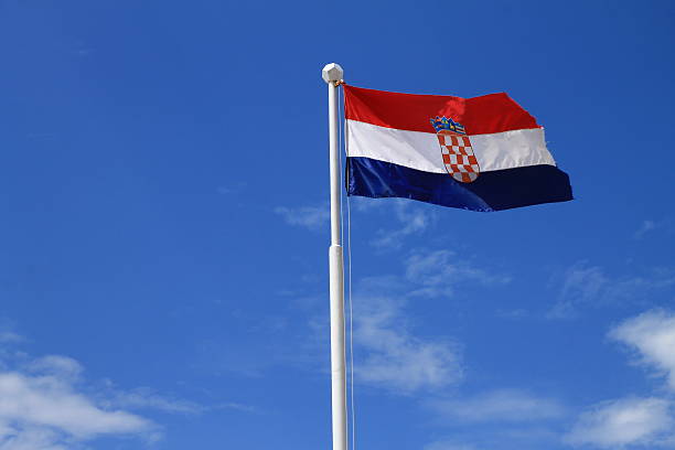 Flag of Croatia with flag pole with blue sky in background stock photo