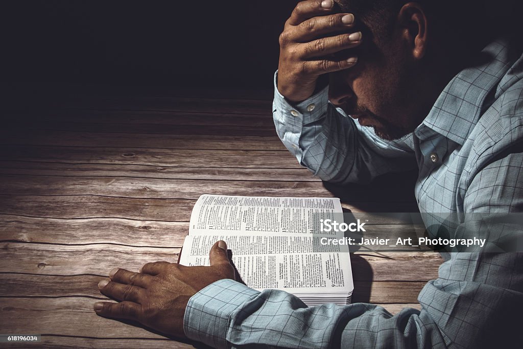 Hombre preocupado leyendo la Santa Biblia - Foto de stock de Biblia libre de derechos