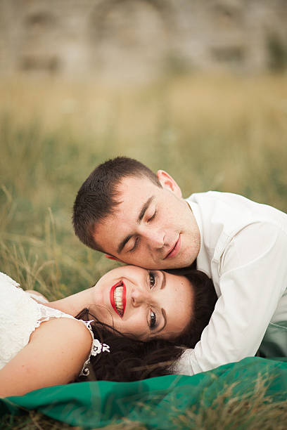 istock Happy wedding couple lying on green grass at the summer 618197478