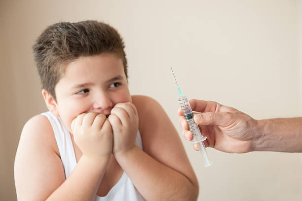 istock thick little boy scared by hand with syringe 618198476