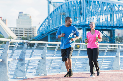 Black couple running together along waterfront in city