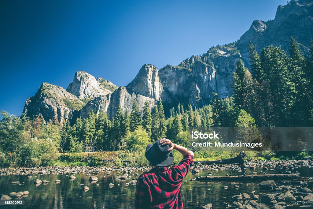 Young woman hiking in majestic landscape A shot of a young woman walking along a river in a majestic landscape. Yosemite National Park Stock Photo