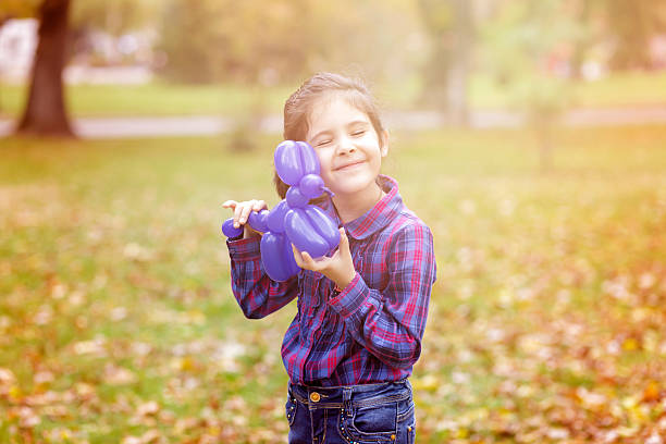 Dreamy girl holds a toy balloon in the park