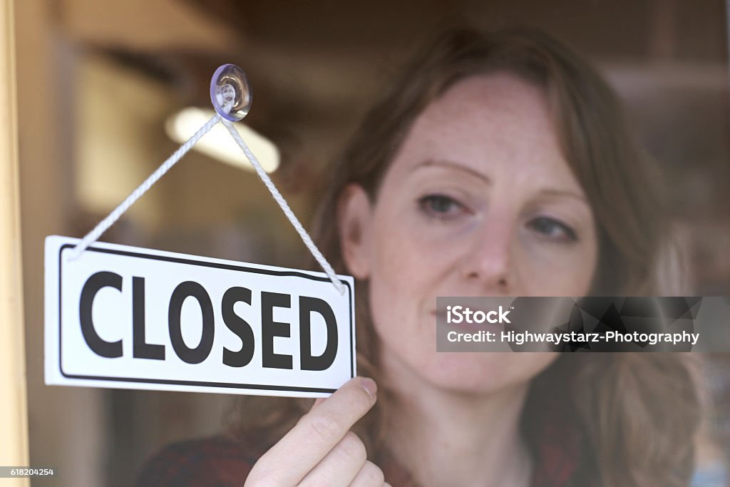 Store Owner Turning Closed Sign In Shop Doorway Going Out Of Business Stock Photo