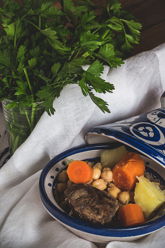 With tagine cooked beef, chickpeas and vegetables. Traditional moroccan cuisine on old wooden tableWith tagine cooked beef, chickpeas and vegetables. Traditional moroccan cuisine on old wooden table