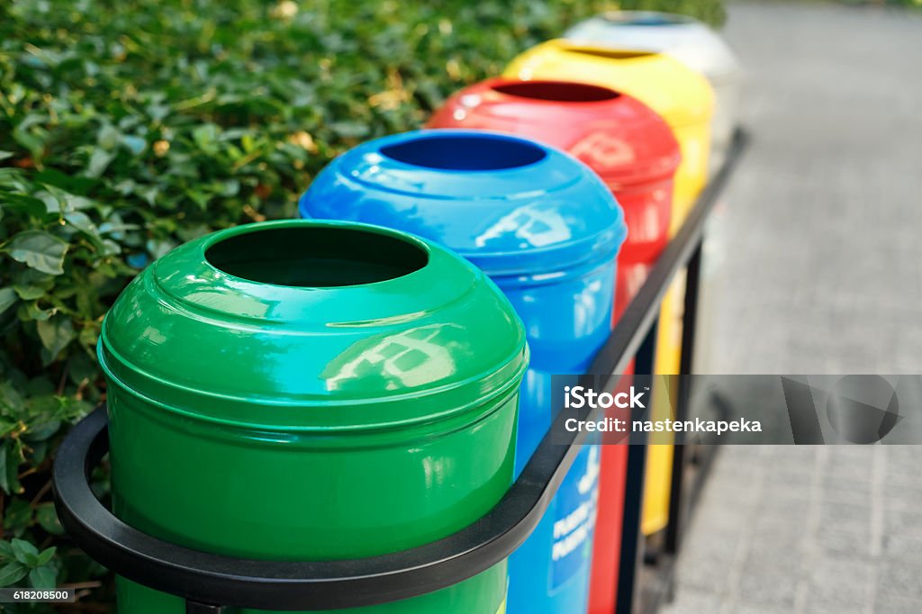 Colored trash containers for garbage separation Colored trash containers for garbage separation. Taking care of nature and ecology. The greenery around. Containers for plastic, paper, glass and metal. Recycling Stock Photo