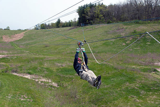 Young man coming down the hill on the rope (zipline)