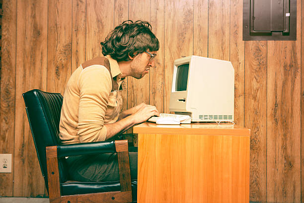 funny nerdy man looking intensely at vintage computer - verdriet fotos stockfoto's en -beelden
