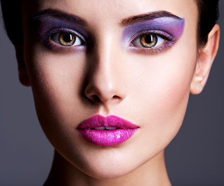 The girl's face closeup with purple eye make-up. fashion makeup. Studio