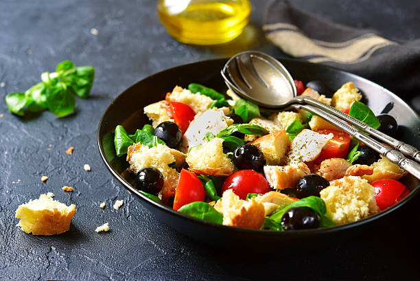 Italian salad panzanella with chicken and lamb`s lettuce. Italian salad panzanella with chicken and lamb`s lettuce on a black concrete or stone background.Vintage style. salad fruit lettuce spring stock pictures, royalty-free photos & images