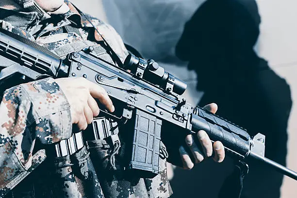 Photo of Soldier with assault rifle, officer give orders