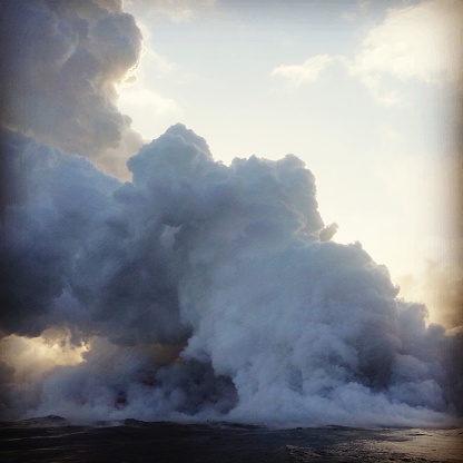 This is a square, color, royalty free stock photograph shot in the Volacano National Park on the Big Island of Kona on the US Hawaii Islands on the rugged coast of the Pacific. The erupting volcano creates a cloud of poisonous, sulphur dioxide smoke. Photographed with a Samsung Galaxy S5 mobile phone.
