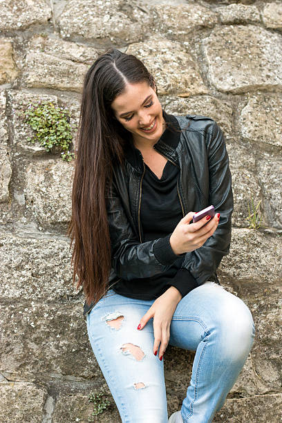 istock Beautiful smiling young girl write messages on mobile phone 618216024